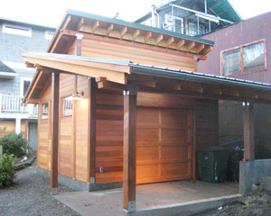 From the opposite side, this new seattle garage remodel has a roll-up door and a carport.  There's also a spot in the corner for recycling and trash containers, custom garage builders Seattle