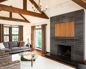 One element that required a complete overhaul was the living room fireplace.  The out-sized brick is now gone, replaced with black slate, and a raised, honed hearth in absolute black granite.  The same quartered walnut cabinets are used to cover a concealed television above the fireplace, with a rolled steel frame