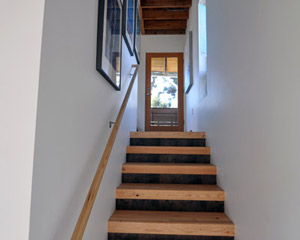 The stairs to the lower level are made from glu-lams, with stained wood risers. The space below hides the water heater.  Each floor has a single Convectaire unit for heat, which keeps the rooms as toasty as they need to be.