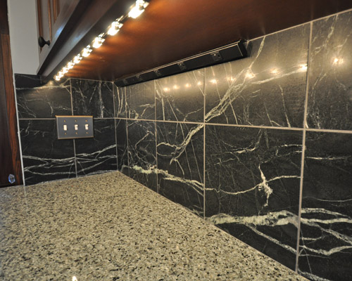 The little things really do matter: Seagull under cabinet lights cast a consistent glow under cabinets while plug mould strips set on a 45 degree angle make them easily accessible and keep the soapstone backsplash free of receptacles
