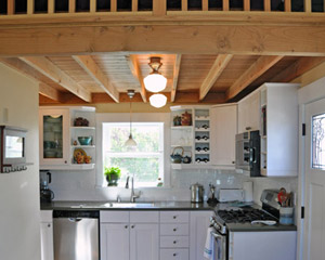 To the right, a functional kitchen takes up one corner of the floor space, with full range, sink and dishwasher.  The fridge is tucked out of sight in the corner. Countertops are Corian with Ikea cabinets