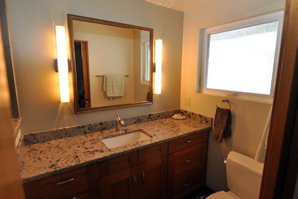 The finished bath is still small, but made to feel bigger with frameless shower door partially over a half wall.  All new tile, Cambria Newhaven counters and updated Kohler plumbing fixtures make for a sleek look