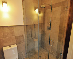 The tile continues at the shower, with slab sea grass used at the threshold.  The relatively small space still feels quite open thanks to the full glass shower surround