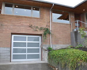 Outside, the old wood garage is replaced with a new frosted glass and aluminum framed beauty.  The fussy black wrought iron railings at the front porch are removed in favor of new stainless stringer railings